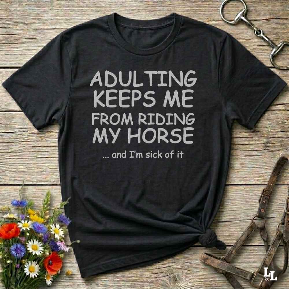 A black graphic t-shirt with white text reading 'ADULTING KEEPS ME FROM RIDING MY HORSE .