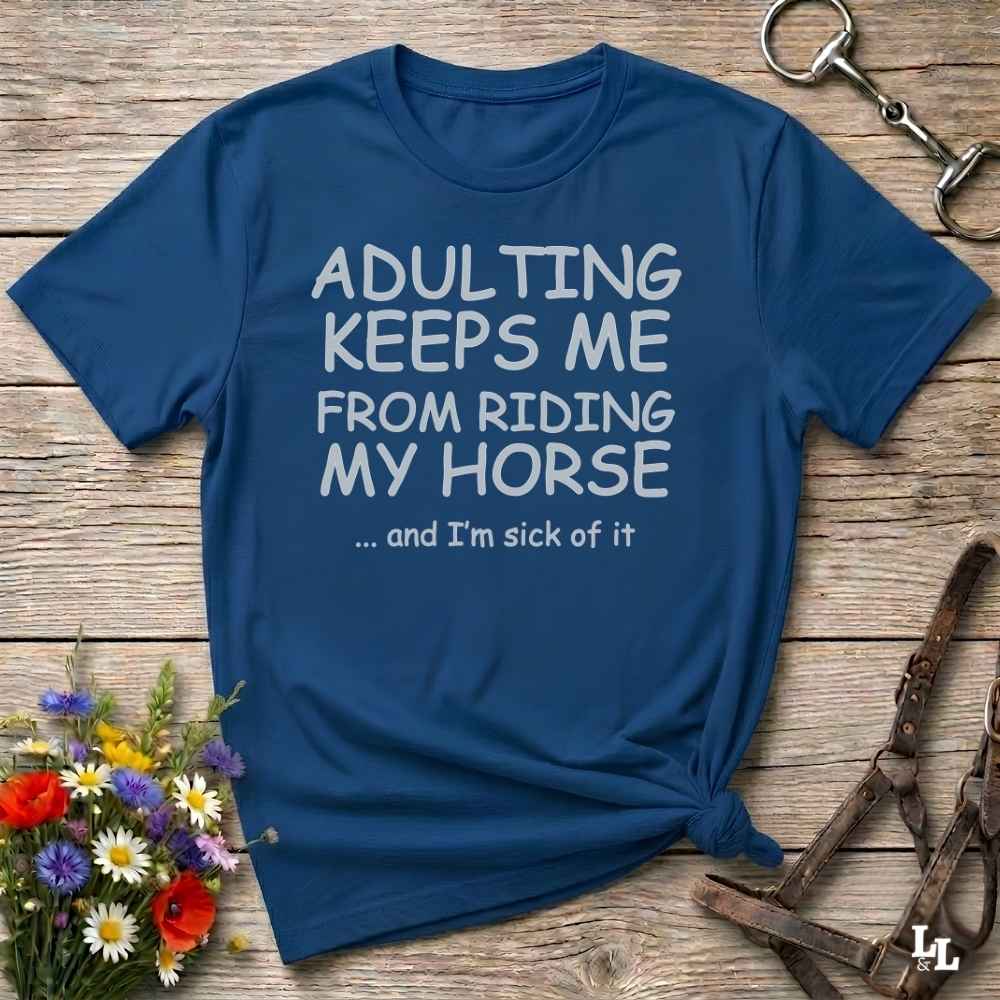 A navy blue graphic t-shirt with white text reading 'ADULTING KEEPS ME FROM RIDING MY HORSE .