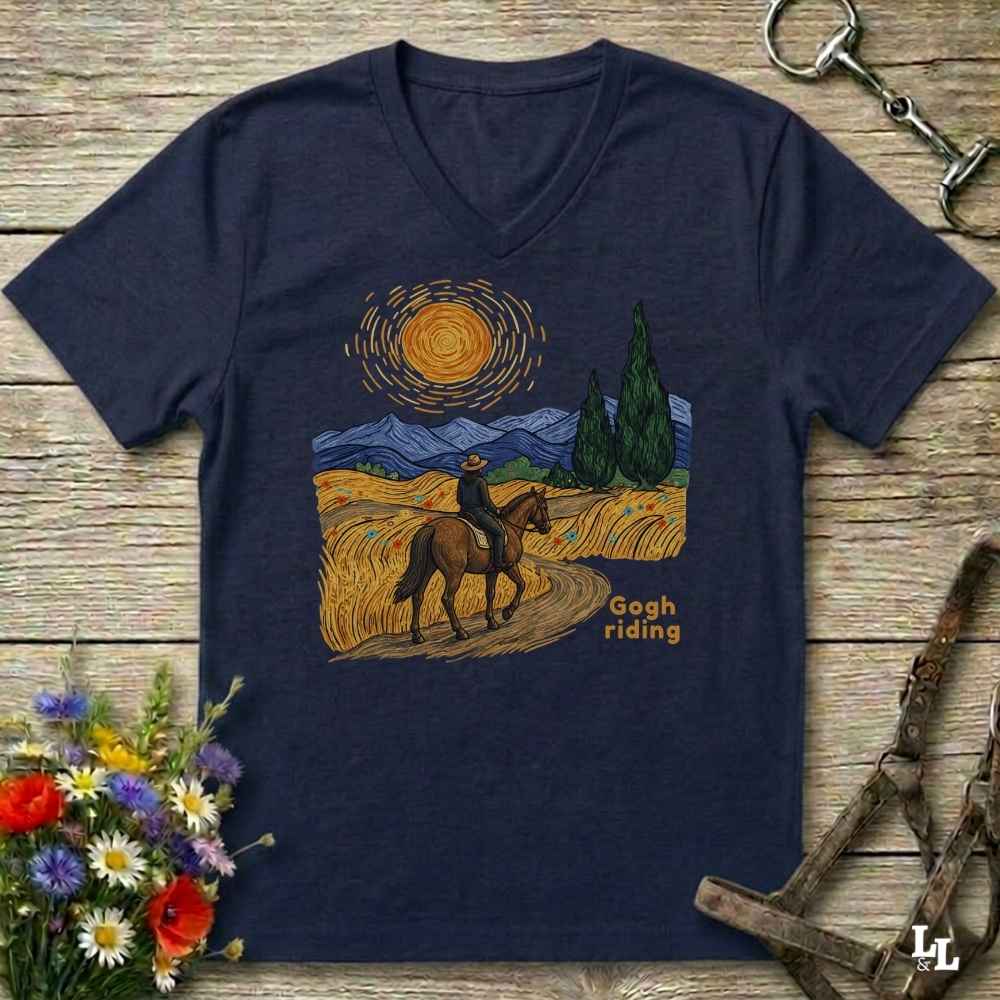 A navy blue V-neck t-shirt laid flat on a rustic wooden surface, featuring a colorful graphic of a rider on a horse in a landscape reminiscent of Van Gogh's Starry Night, with the text 'Gogh riding'.