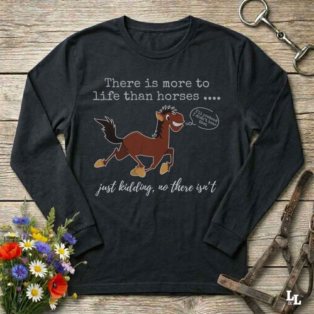 Black long-sleeve t-shirt with a humorous horse graphic and text, displayed in a flat-lay arrangement on a rustic wooden background with flowers and equestrian accessories.