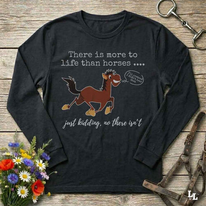 Black long-sleeve t-shirt with a humorous horse graphic and text, displayed in a flat-lay arrangement on a rustic wooden background with flowers and equestrian accessories.