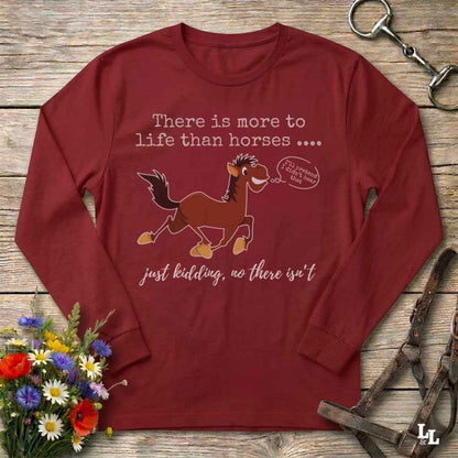 Red  long-sleeve t-shirt with a humorous horse graphic and text, displayed in a flat-lay arrangement on a rustic wooden background with flowers and equestrian accessories.
