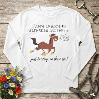 A white long-sleeve t-shirt with a humorous horse graphic and text, displayed in a flat-lay arrangement on a rustic wooden background with flowers and equestrian accessories.