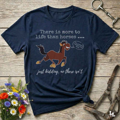 Navy blue t-shirt with horse graphic and text on a wooden surface with flowers and equestrian tools.