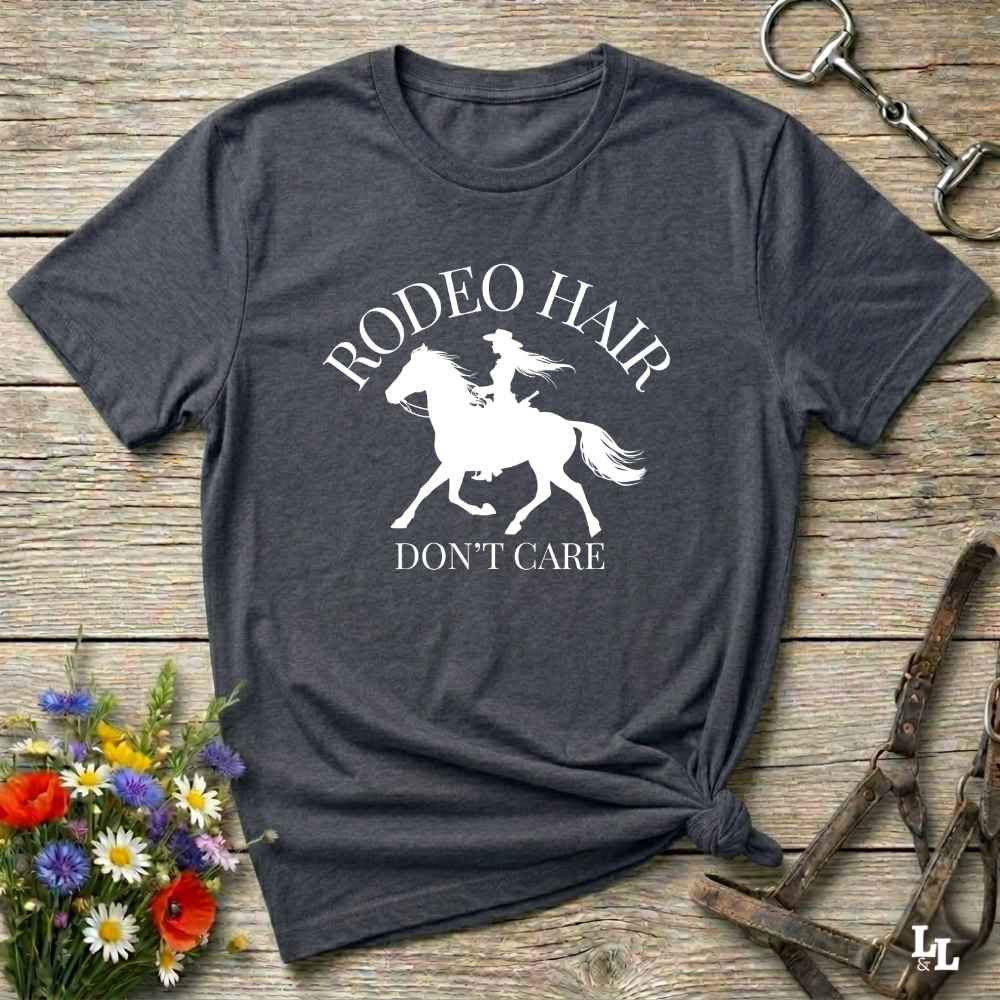 typography cowgirl t-shirt styled for rodeo lovers and horse girls on rustic wooden background. Trendy cowgirl shirt designed for horse lovers, featuring bold western lettering in graphic style. Horse riding themed t-shirt with country slogan “Rodeo Hair Don’t Care” styled for modern cowgirls.