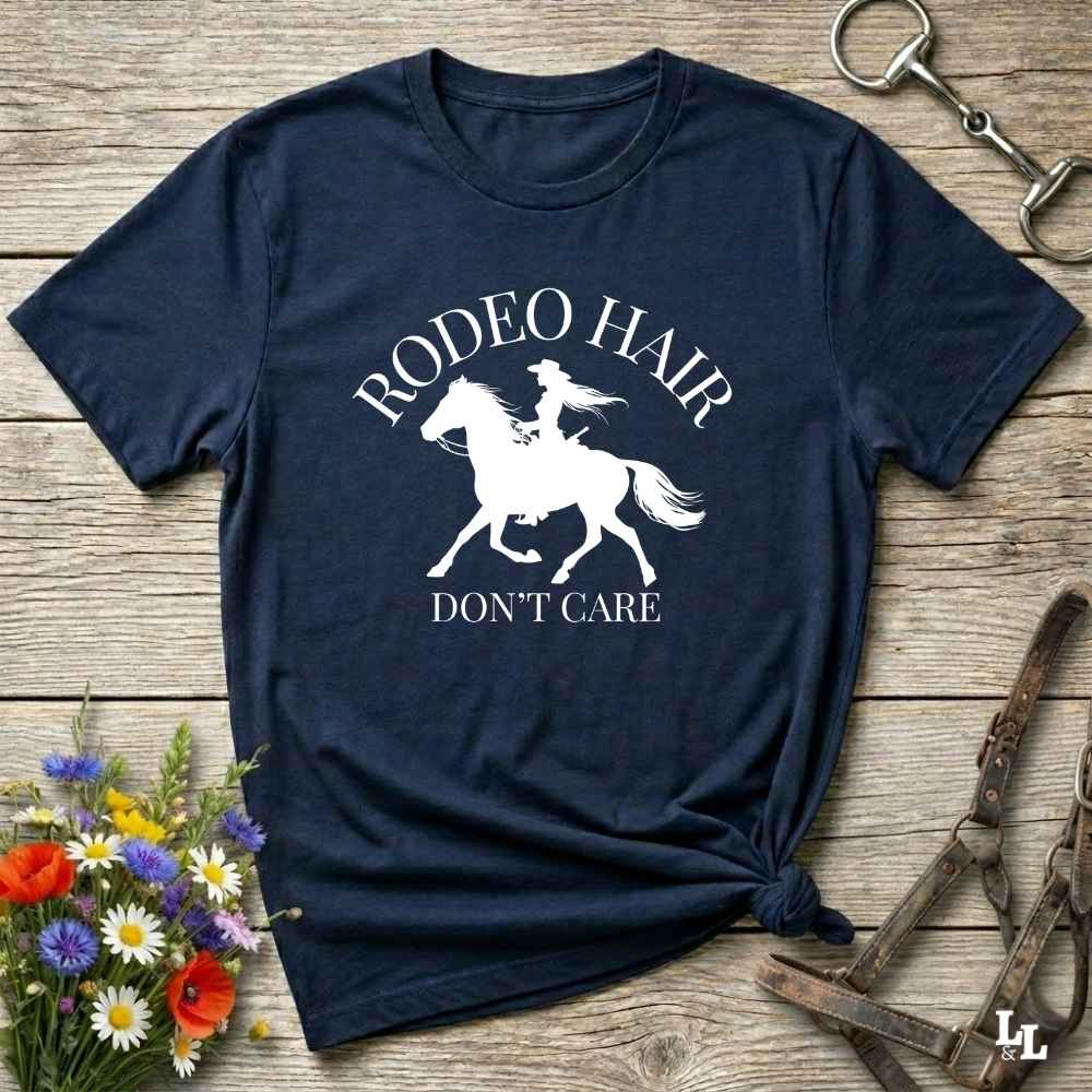 typography cowgirl t-shirt styled for rodeo lovers and horse girls on rustic wooden background. Trendy cowgirl shirt designed for horse lovers, featuring bold western lettering in graphic style. Horse riding themed t-shirt with country slogan “Rodeo Hair Don’t Care” styled for modern cowgirls.