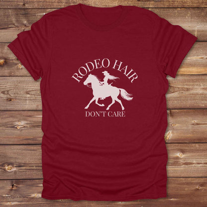 ypography cowgirl t-shirt styled for rodeo lovers and horse girls on rustic wooden background. Trendy cowgirl shirt designed for horse lovers, featuring bold western lettering in graphic style. Horse riding themed t-shirt with country slogan “Rodeo Hair Don’t Care” styled for modern cowgirls.