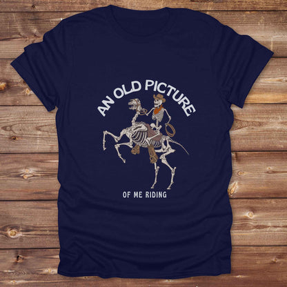 Saddle up with spooky western vibes in this skeleton cowboy “Old Picture of Me Riding” shirt, perfect for rodeo lovers and Halloween humor fans. This cowboy skeleton t-shirt combines retro western style with dark humor, ideal for ranchers, riders, and funny costume alternatives. Make fall fashion unforgettable with this witty, rustic western parody tee featuring bones, boots, and bold cowboy nostalgia.