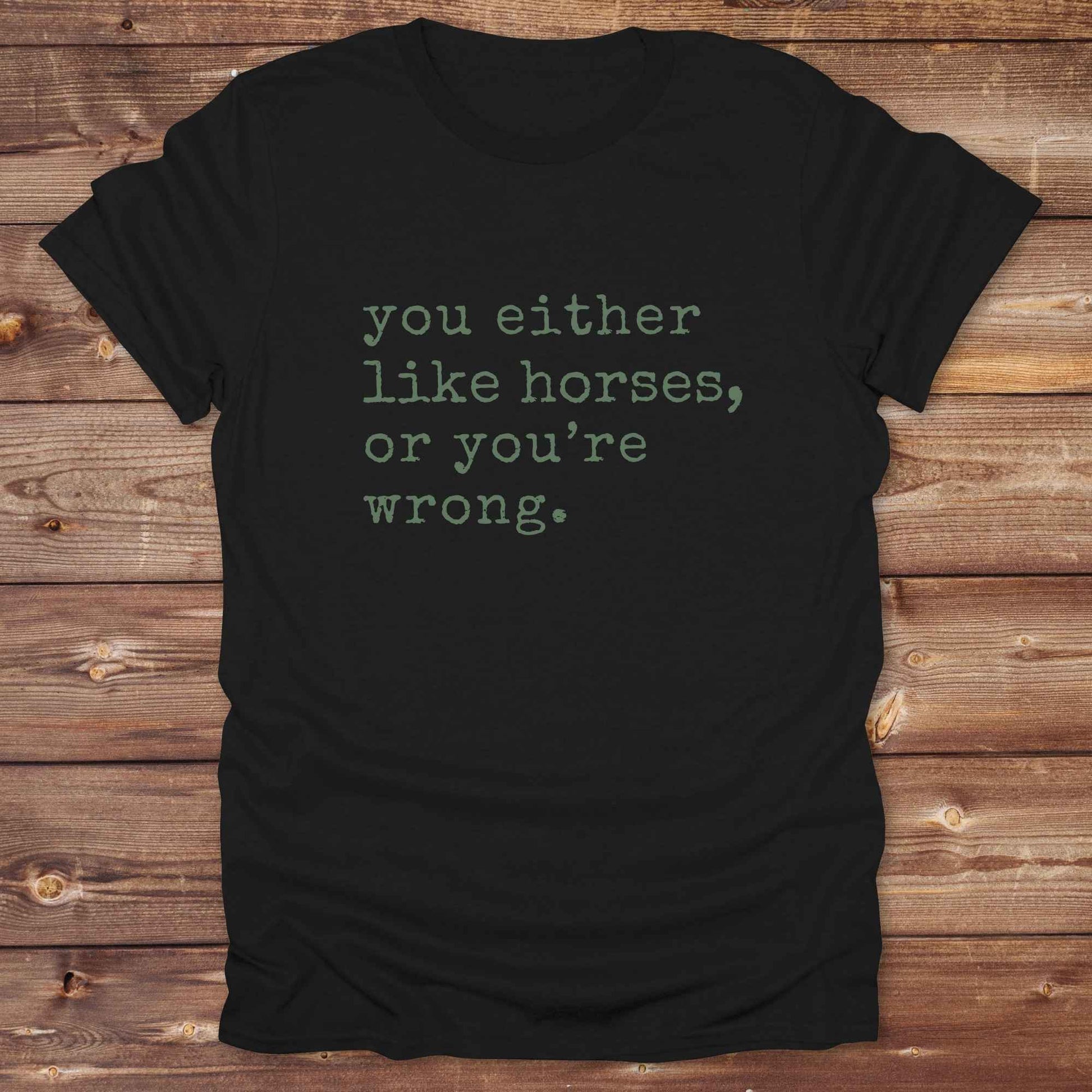 Black t-shirt with text 'you either like horses, or you're wrong.' on a wooden surface. Show your love for horses loud and proud with this funny typography western tee ,perfect for cowgirls, ranchers, and equestrians. 
This “You either like horses or you're wrong” t-shirt is a hilarious must have for horse lovers with sass and sarcasm. Ideal gift for any horse girl or cowboy, this rustic western Gildan tee blends humor with horse life perfectly. Whether you’re mucking stalls or riding trails, this sarcastic