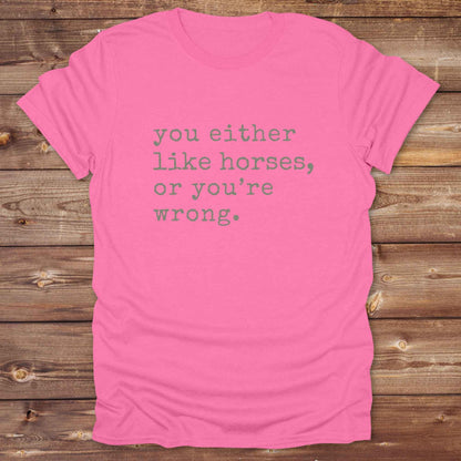 Pink t-shirt with text 'you either like horses, or you're wrong.' on a wooden background. Show your love for horses loud and proud with this funny typography western tee ,perfect for cowgirls, ranchers, and equestrians. 
This “You either like horses or you're wrong” t-shirt is a hilarious must have for horse lovers with sass and sarcasm. Ideal gift for any horse girl or cowboy, this rustic western Gildan tee blends humor with horse life perfectly. Whether you’re mucking stalls or riding trails, this sarcast