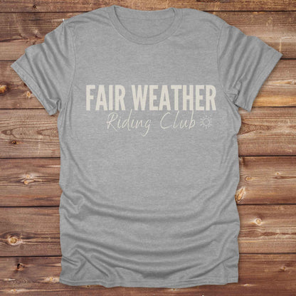"Fair Weather Riding Club” tee brings western charm and playful equestrian humor together in a bold design that speaks to cowboys and cowgirls alike. erfect for horse lovers who only ride in sunshine. Featuring clean typography and a cute sun icon, it’s the ultimate cowboy core essential for rodeo days, trail rides, or just lounging in the barn. Whether it’s for yourself or as a gift for a fellow rider, this western quote tee adds a sunny twist to any rustic outfit. must have for any modern day trailblazer.
