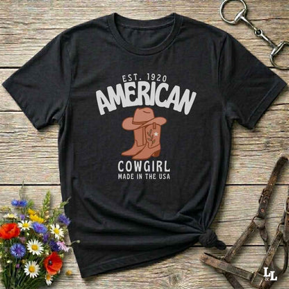 This American Cowgirl T-Shirt is the perfect mix of bold western pride and boho rodeo style. Featuring a rustic boot and hat graphic, it's made for country girls who live for rodeo season and horse rides. It’s a statement piece for cowgirls, country lovers, and western fashion fans alike. Whether you’re gifting it for a birthday or styling it for your next state fair, this tee brings serious cowboy core energy to your closet.  A must have for horse lovers.
