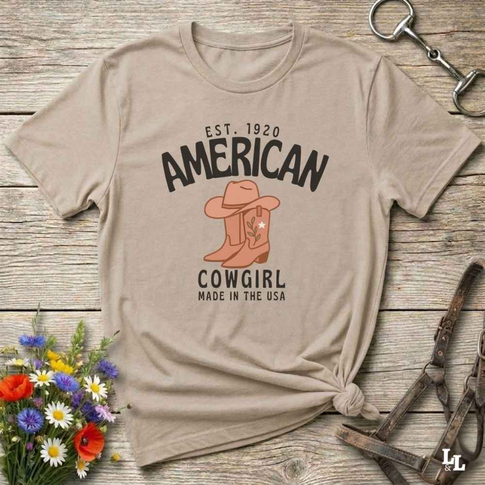 This American Cowgirl T-Shirt is the perfect mix of bold western pride and boho rodeo style. Featuring a rustic boot and hat graphic, it's made for country girls who live for rodeo season and horse rides. It’s a statement piece for cowgirls, country lovers, and western fashion fans alike. Whether you’re gifting it for a birthday or styling it for your next state fair, this tee brings serious cowboy core energy to your closet.  A must have for horse lovers.