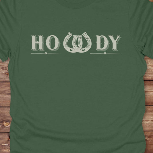 Say “Howdy” in true western style with this rustic horseshoe tee designed for cowboys, cowgirls, and horse lovers alike. Featuring a bold western font and a double horseshoe “W,” this shirt blends southern charm with modern rodeo flair. It's perfect for birthdays, rodeo weekends, country fairs, or just everyday ranch life. Whether you're a rancher, rider, or rural rebel, this shirt adds a little yeehaw to your wardrobe.