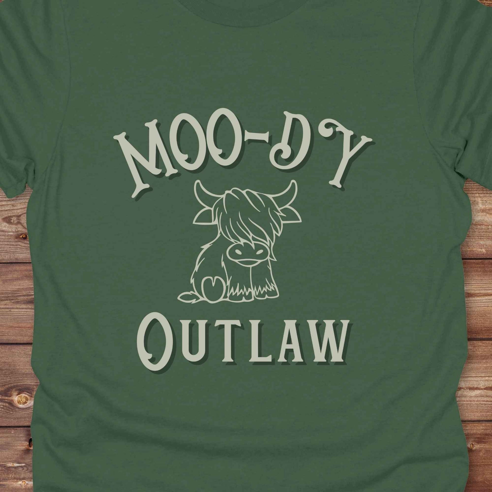 Meet the “Moo-Dy Outlaw” tee from Lasso and Loom a perfect mix of western sass and farmyard fun. Featuring a hand drawn moody Highland cow and outlaw typography, this western graphic tee is made for cowgirls, cowboys, and everyone who rides through life with a little attitude. It's ideal for rodeos, ranch days, and social media selfies with rustic vibes and comfort in every stitch. Whether you're shopping for yourself or gifting a cow lover with a sense of humor, this shirt is guaranteed to wrangle smiles