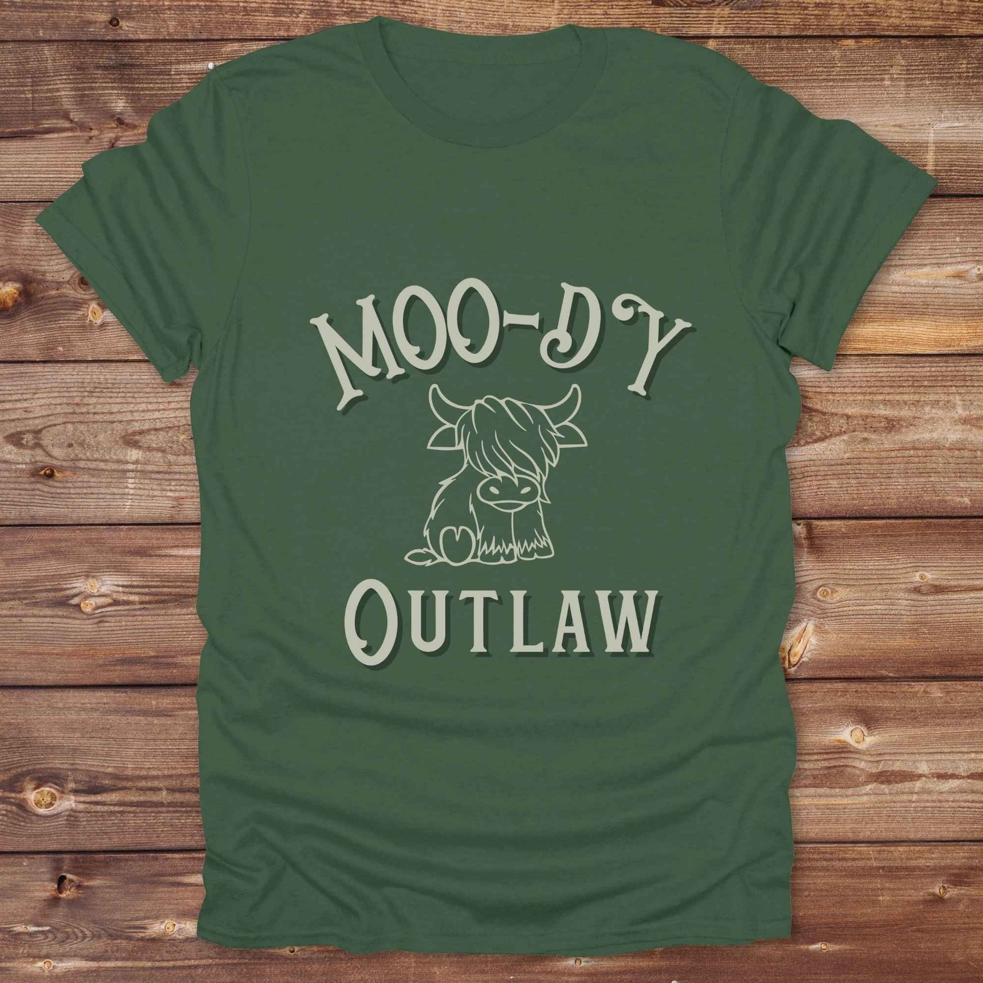 Meet the “Moo-Dy Outlaw” tee from Lasso and Loom a perfect mix of western sass and farmyard fun. Featuring a hand drawn moody Highland cow and outlaw typography, this western graphic tee is made for cowgirls, cowboys, and everyone who rides through life with a little attitude. It's ideal for rodeos, ranch days, and social media selfies with rustic vibes and comfort in every stitch. Whether you're shopping for yourself or gifting a cow lover with a sense of humor, this shirt is guaranteed to wrangle smiles