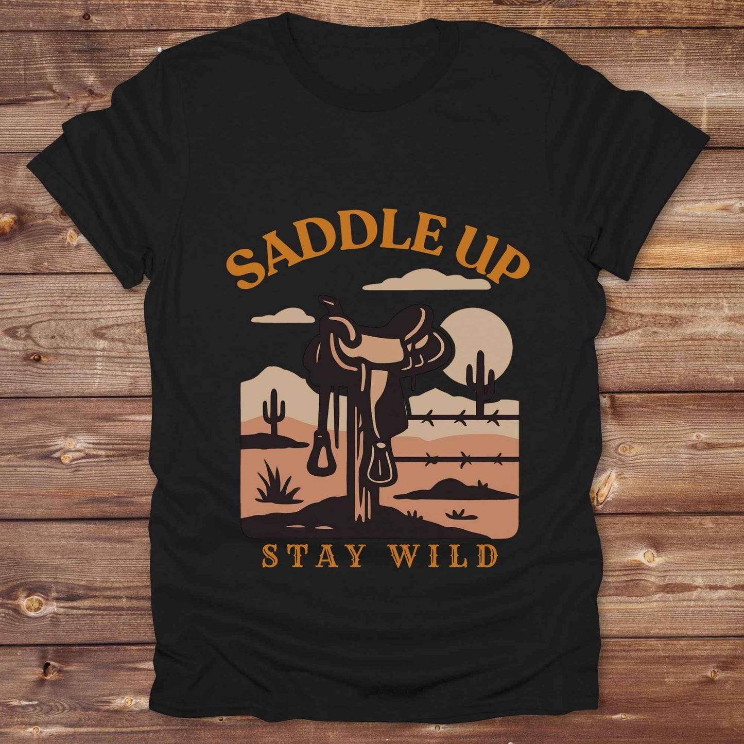 Saddle Up Stay Wild western t-shirt features a bold desert sunset graphic with a classic saddle and western landscape. Perfect for cowgirls, cowboys, and horse lovers, this rustic tee blends adventure with comfort and country charm. Whether you're heading to a rodeo, trail ride, or simply embracing your wild side, this shirt offers a soft fit and bold design. Designed for western wear fans, equestrians, and country souls, it's a must have for anyone who lives the saddle life. 
