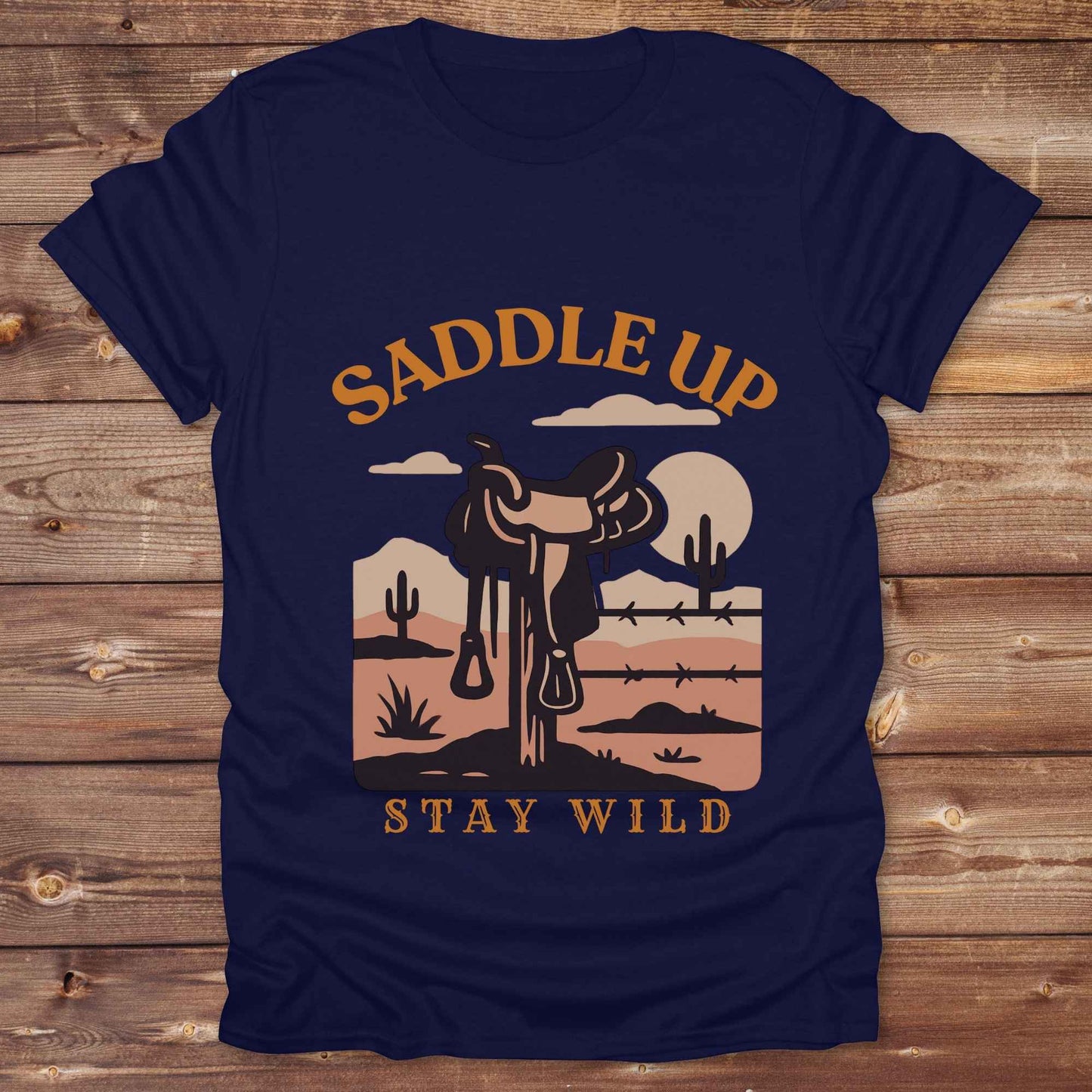 Saddle Up Stay Wild western t-shirt features a bold desert sunset graphic with a classic saddle and western landscape. Perfect for cowgirls, cowboys, and horse lovers, this rustic tee blends adventure with comfort and country charm. Whether you're heading to a rodeo, trail ride, or simply embracing your wild side, this shirt offers a soft fit and bold design. Designed for western wear fans, equestrians, and country souls, it's a must have for anyone who lives the saddle life. 