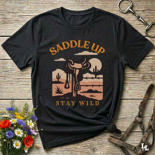 Saddle Up Stay Wild western black t-shirt features a bold desert sunset graphic with a classic saddle and western landscape. Perfect for cowgirls, cowboys, and horse lovers, this rustic tee blends adventure with comfort and country charm. Whether you're heading to a rodeo, trail ride, or simply embracing your wild side, this shirt offers a soft fit and bold design. Designed for western wear fans, equestrians, and country souls, it's a must have for anyone who lives the saddle life. 