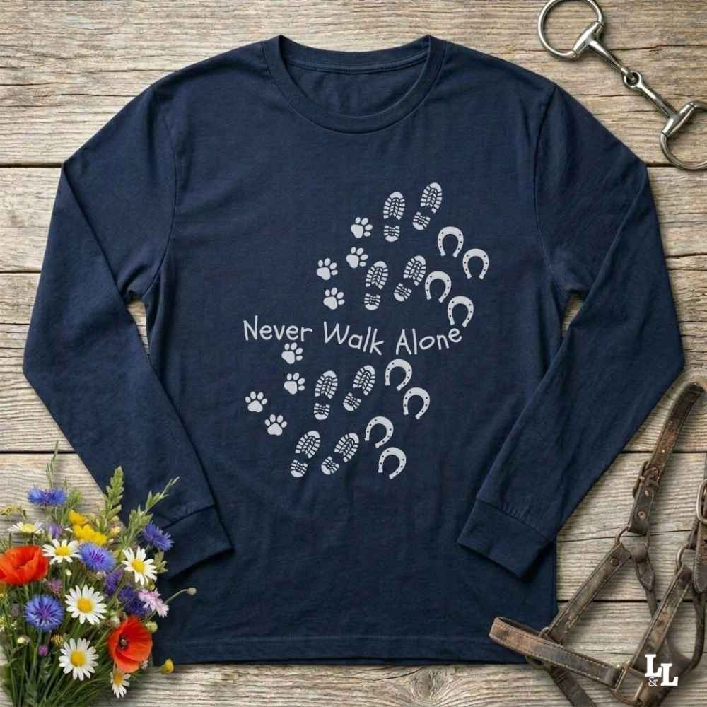 Navy blue long-sleeve shirt with shoe and paw print design on a wooden surface with flowers and equestrian equipment.
