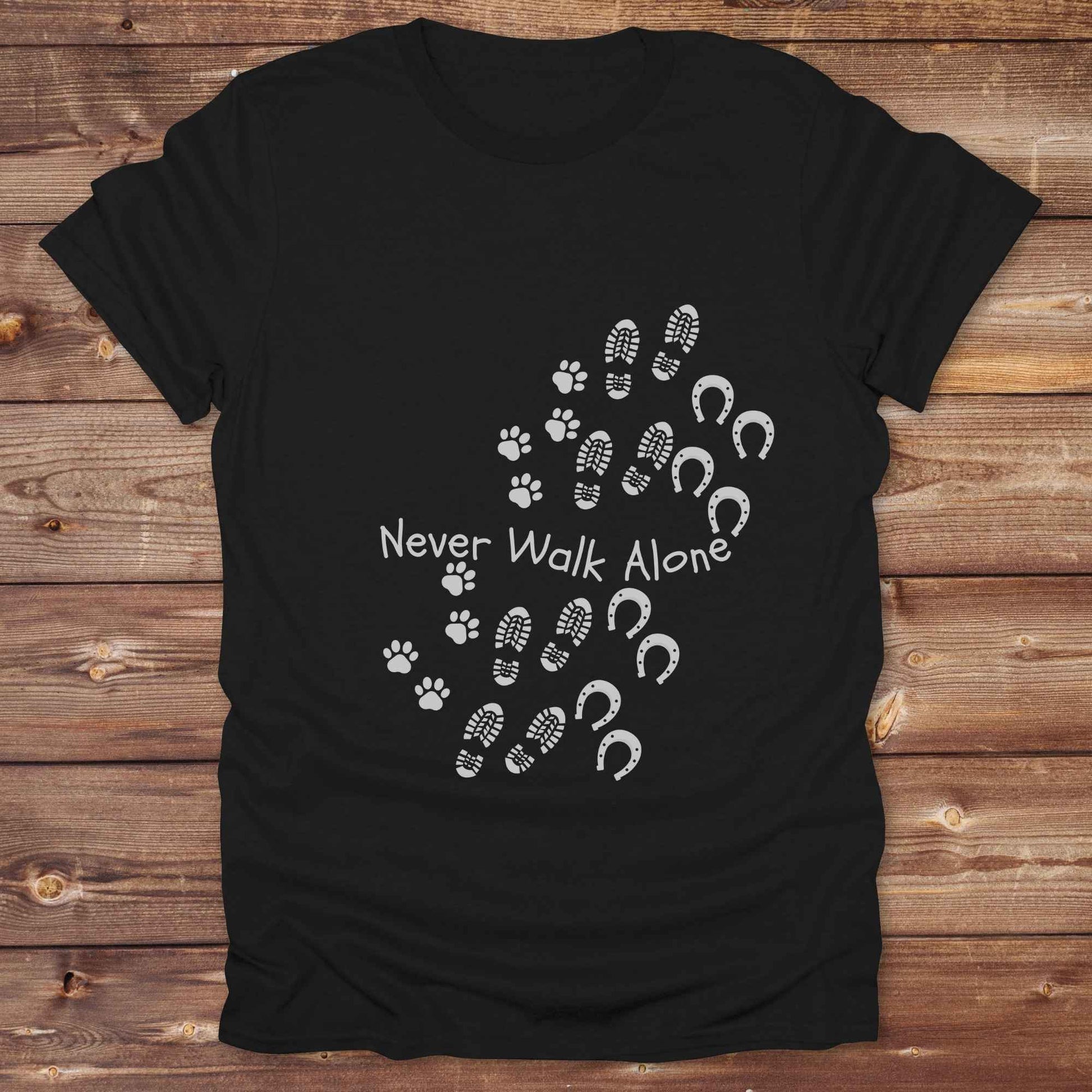 Celebrate the unbreakable bond between dogs, horses, and their human companions with this heartfelt "Never Walk Alone" western-style t-shirt. Featuring boot, paw, and hoof prints in a soft rustic print, this tee is perfect for cowgirls, dog moms, horse lovers, and equestrian trail riders alike. Whether you're walking through a ranch, riding across fields, or heading to the stables, this shirt is a perfect fit for your country lifestyle. Makes a thoughtful gift for birthdays, pet memorials, and western pet l