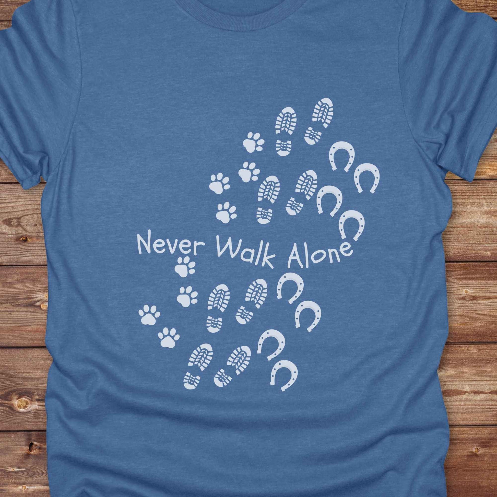 Celebrate the unbreakable bond between dogs, horses, and their human companions with this heartfelt "Never Walk Alone" western-style t-shirt. Featuring boot, paw, and hoof prints in a soft rustic print, this tee is perfect for cowgirls, dog moms, horse lovers, and equestrian trail riders alike. Whether you're walking through a ranch, riding across fields, or heading to the stables, this shirt is a perfect fit for your country lifestyle. Makes a thoughtful gift for birthdays, pet memorials, and western pet l