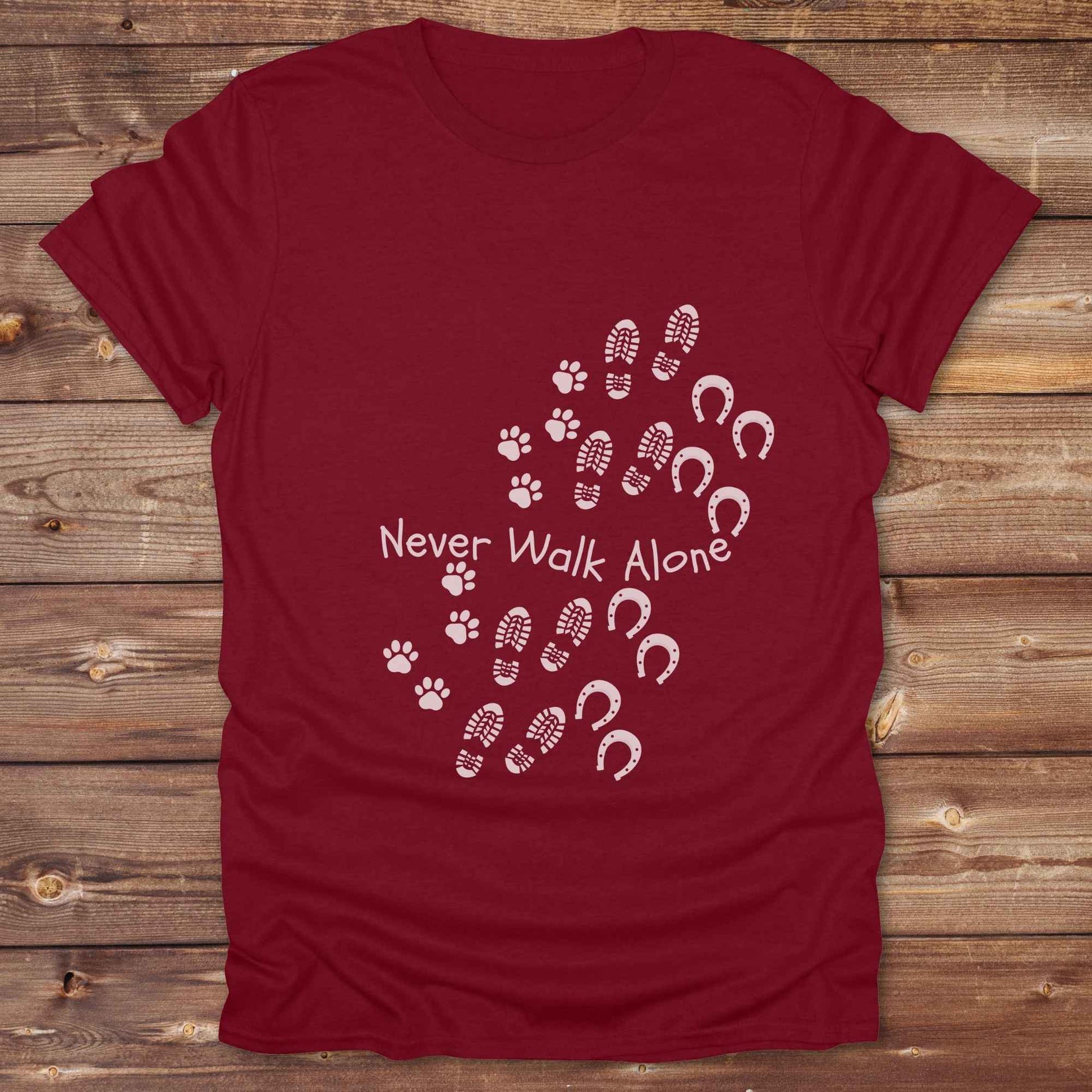 Celebrate the unbreakable bond between dogs, horses, and their human companions with this heartfelt "Never Walk Alone" western-style t-shirt. Featuring boot, paw, and hoof prints in a soft rustic print, this tee is perfect for cowgirls, dog moms, horse lovers, and equestrian trail riders alike. Whether you're walking through a ranch, riding across fields, or heading to the stables, this shirt is a perfect fit for your country lifestyle. Makes a thoughtful gift for birthdays, pet memorials, and western pet l