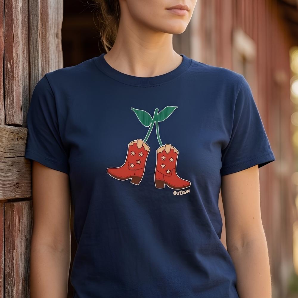 Person wearing a navy blue t-shirt with red cowboy boots and 'Outlaw' text design outside  wooden barn. Cherry Cowboy Boots T-Shirt for Horse Lovers, Equestrian Wear, Perfect gift for Horse Riders, horse girl shirt, horse mom shirt, horse lover, horse girl, Funny horse lover gifts, Funny horse shirts, Horse girl gifts, Equestrian graphic tees, fathers day gift, Sarcastic horse shirt