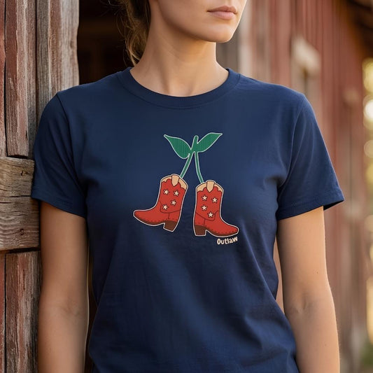 Person wearing a navy blue t-shirt with red cowboy boots and 'Outlaw' text design outside  wooden barn. Cherry Cowboy Boots T-Shirt for Horse Lovers, Equestrian Wear, Perfect gift for Horse Riders, horse girl shirt, horse mom shirt, horse lover, horse girl, Funny horse lover gifts, Funny horse shirts, Horse girl gifts, Equestrian graphic tees, fathers day gift, Sarcastic horse shirt