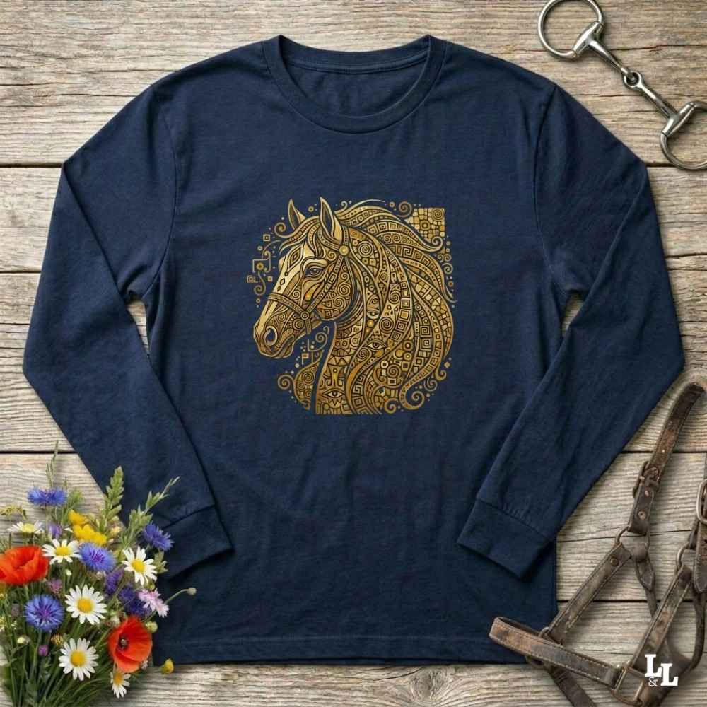 A navy blue long-sleeve t-shirt with a detailed gold horse head graphic on the chest, styled in a flat-lay on a rustic wooden background with equestrian and floral props.